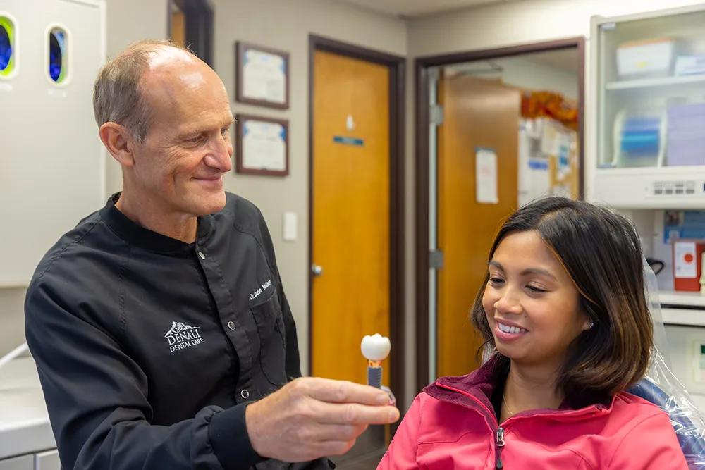 Dr. Maisey showing a patient a dental implant and crown